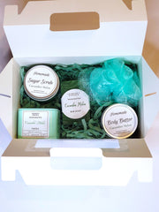 A green bath set including a handmade soap bar, sugar scrub, body butter, candle, and loofah scented in Cucumber melon