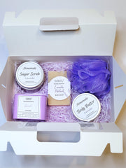 A purple bath set including a handmade soap bar, sugar scrub, body butter, candle, and loofah scented in lavender