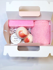 A pink bath set including two pedi bombs, a 1oz. body butter, a pumice stone , and cozy socks scented in peach