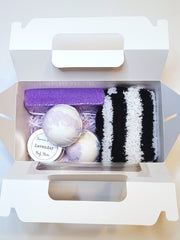 A purple bath set including two pedi bombs, a 1oz. body butter, a pumice stone , and cozy socks scented in lavender
