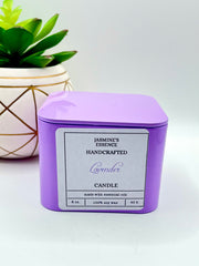 A Lavender Scented candle with a wooden crackle wick in an 8oz. lavender purple square tin with a label that reads: “Jasmine’s Essence Handcrafted Lavender Candle”