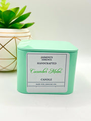 A Cucumber Melon Scented candle with a wooden crackle wick in an 8oz. Light Green square tin with a label that reads: “Jasmine’s Essence Handcrafted Cucumber Melon Candle”